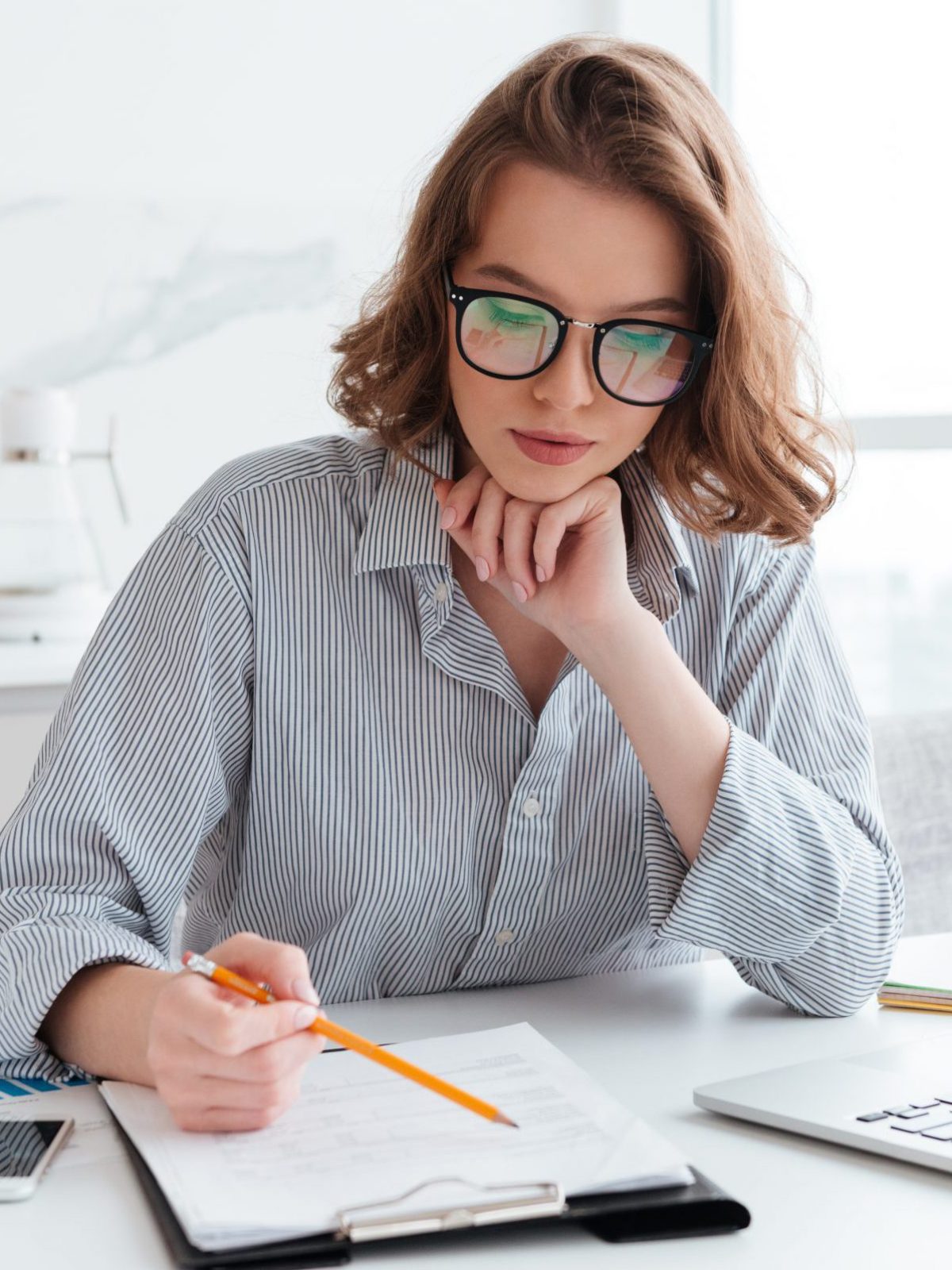 young-concentrated-businesswoman-glasses-striped-shirt-working-with-papers-home-scaled-e1694699643792
